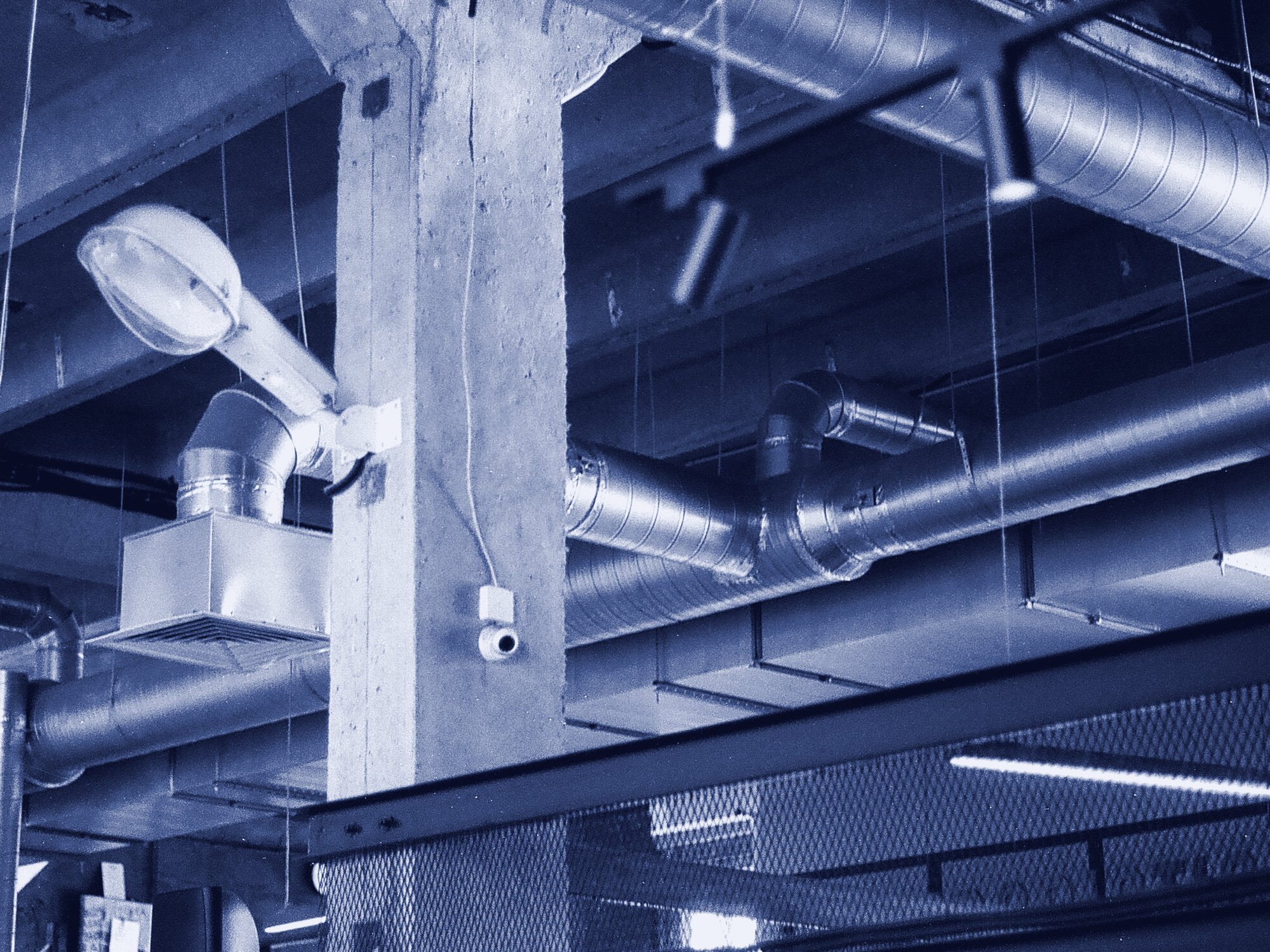 A small dome camera mounted on a concrete column, below exposed ductwork.